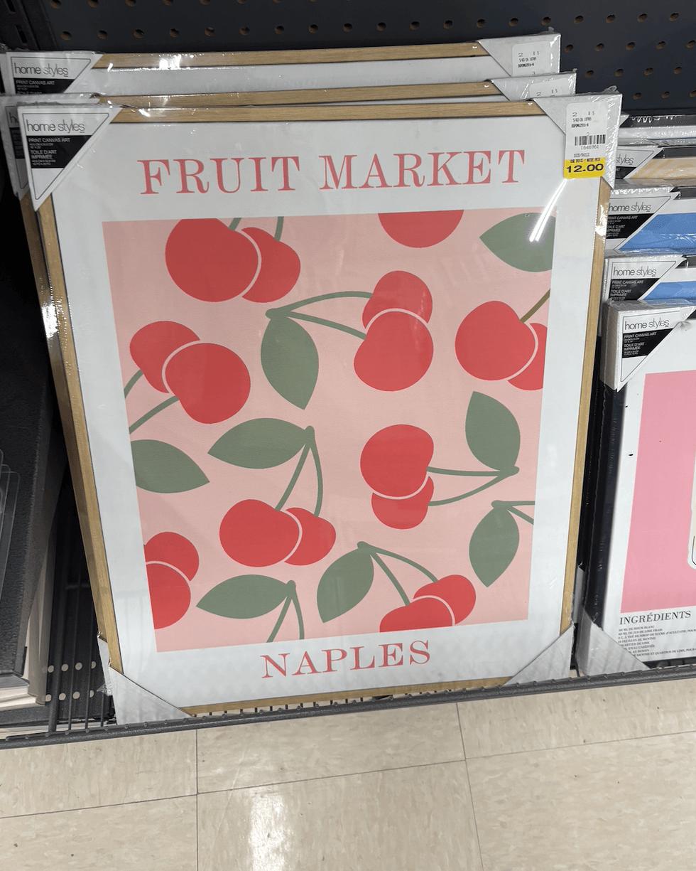 Une toile encadr\u00e9e illustrant des cerises rouges sur un fond rose avec les inscriptions \u00ab Fruit Market \u00bb et \u00ab Naples \u00bb.