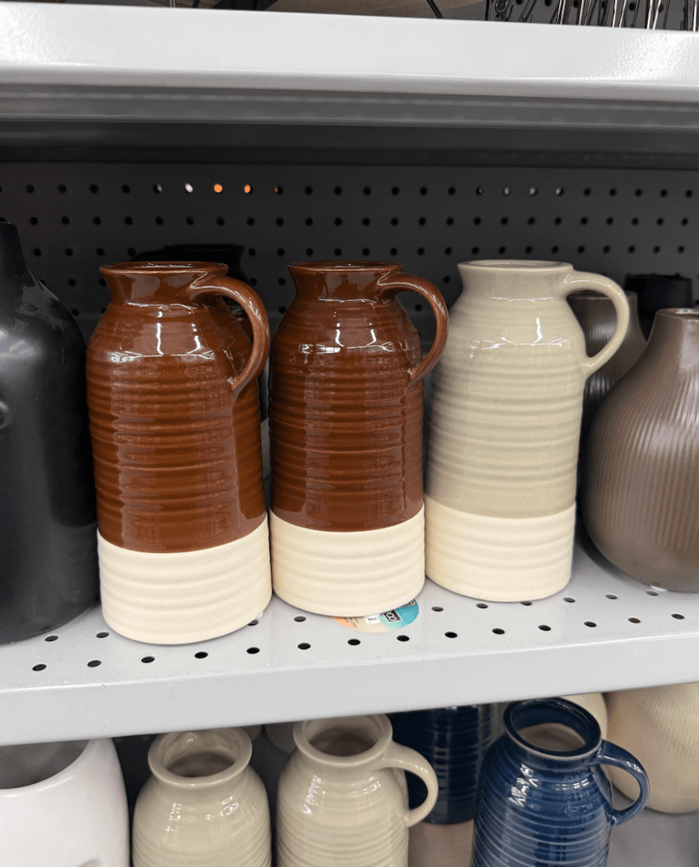 Vases pichets en c\u00e9ramique deux tons, avec anse et corps stri\u00e9, offerts en bleu marine, brun, beige et cr\u00e8me, vendus 4,50 $ chez Dollarama.