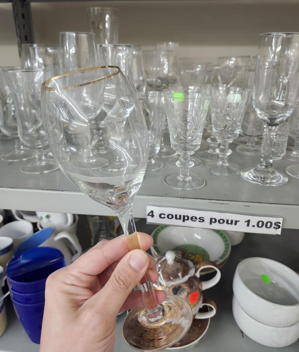 Verre \u00e0 vin devant une \u00e9tag\u00e8re remplie de vaisselle.