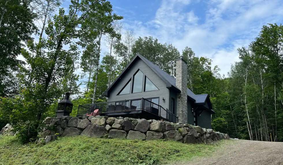 Vu du bas sur un chalet noir en nature.