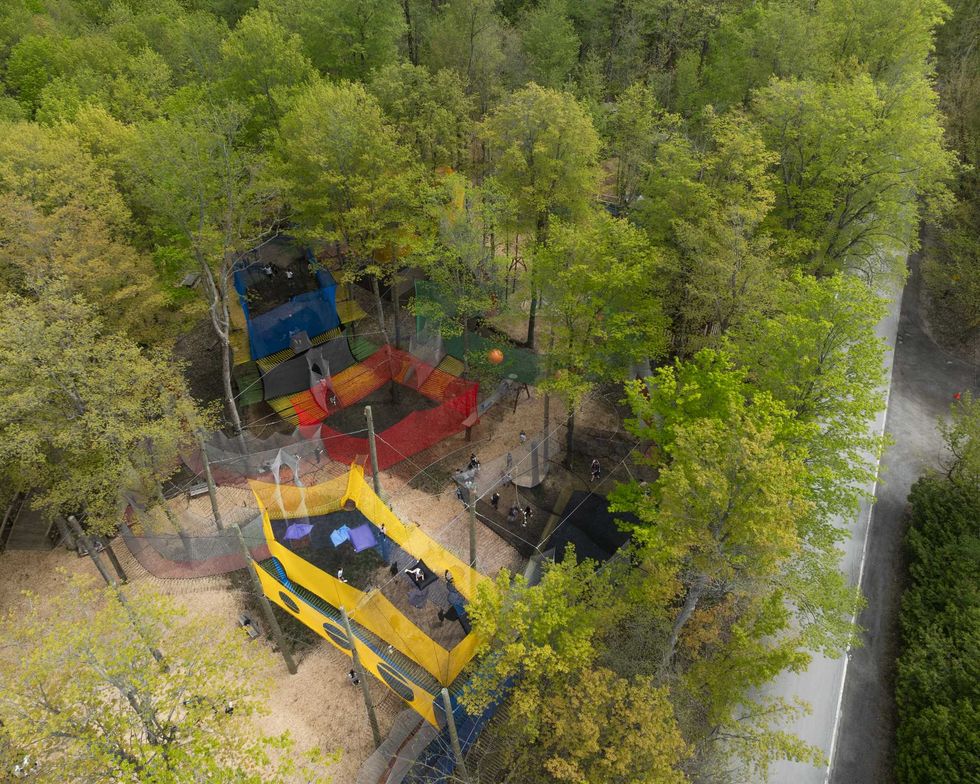 Vue a\u00e9rienne du parc upl\u00e5 Mont-Saint-Gr\u00e9goire avec ses filets suspendus color\u00e9s install\u00e9s au c\u0153ur de la for\u00eat.