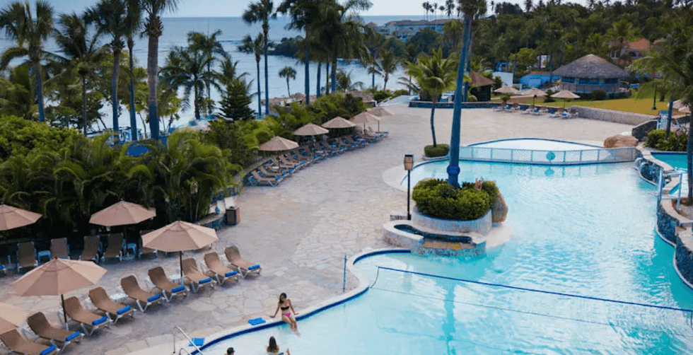 Vue a\u00e9rienne sur une piscine, les palmiers et la plage de l'h\u00f4tel Lifestyle Tropical Beach Resort and Spa \u00e0 Puerto Plata en R\u00e9publique dominicaine.